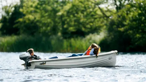 Due persone distese su una barca sull'acqua con un motore Honda.