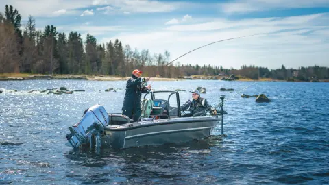 Due uomini pescano su una barca con motori gemelli Honda BF60 in acqua.