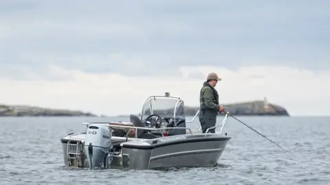 Signore che pesca su una barca con motore Honda BF60.