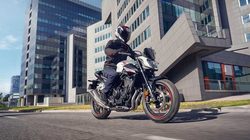 Modella alla guida di una motocicletta in un contesto urbano.